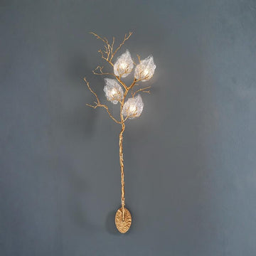 Decorative wall light fixture with gold branch and glass shades on a dark gray background