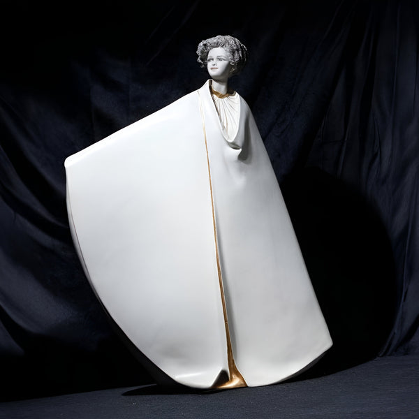 Statue of a woman in a white robe with gold accents on a dark background from Sibania, available at Spacio retail store in Mumbai. 
