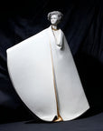 Statue of a woman in a white robe with gold accents on a dark background from Sibania, available at Spacio retail store in Mumbai. 