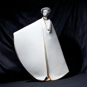 Statue of a woman in a white robe with gold accents on a dark background from Sibania, available at Spacio retail store in Mumbai. 