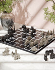 An architectural Indian monuments chess game with black and silver city-piece pieces on a black board, styled on a wooden board with Indian map with potted plants in the background.