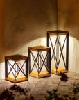 Set of three wooden outdoor lanterns with metal frames against a textured wall  by Les Jardins available at Spacio retail stores in Mumbai & Kolkata. 