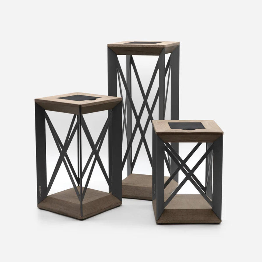 Three wooden and metal outdoor indoor solar light lanterns with black metal frames on a white background by Les Jardins available at Spacio retail stores in Mumbai & Kolkata. 