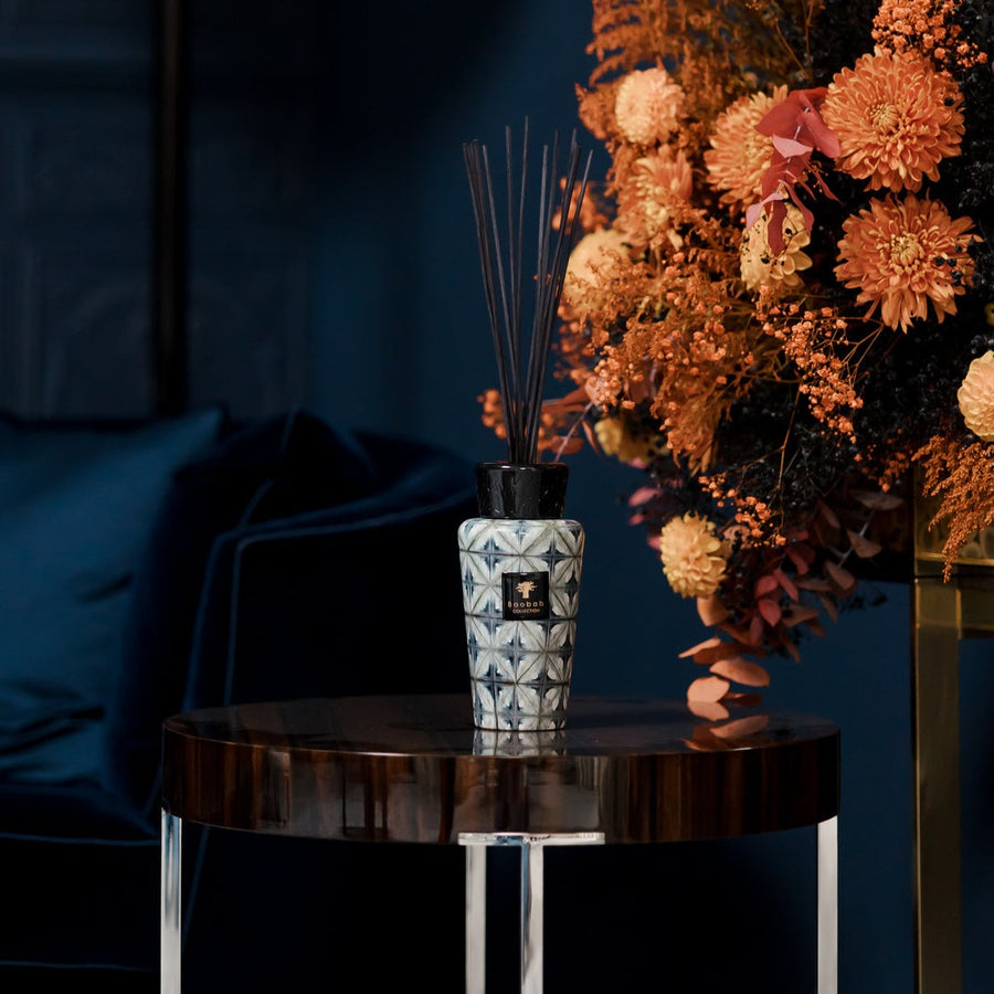 A Baobab Boho Kilan Diffuser DIF500BKI on a table in front of a blue couch, emitting a lovely fragrance.