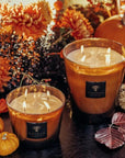 A table adorned with Baobab Cuir De Russie Candle Max 10 MAX10CUR scented candles and pumpkins.