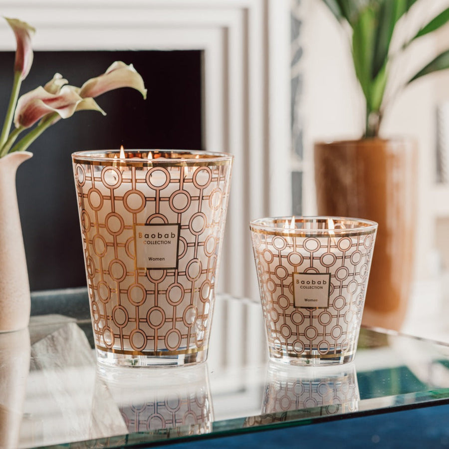 A Baobab Women Candle MAX16WOM is sitting on a table next to a vase, symbolizing support for the Breast Cancer Foundation and empowering women.