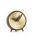 A Nomon wooden clock with a walnut stand on a white background.