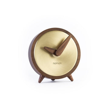 A Nomon wooden clock with a walnut stand on a white background.