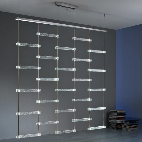 A room with a Italamp Piola lighting fixture hanging from the ceiling, featuring Italamp and cast glass bars.