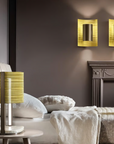 A bedroom with a yellow Masiero Ebe Wall Sconce from the Masiero Ebe Collection, illuminating the space with its luxury lighting and creating a cozy atmosphere alongside a fireplace.