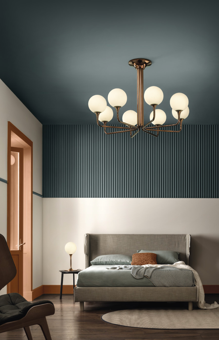 A bedroom with blue walls and a bed featuring the Masiero Tee Chandelier for luxury lighting from Masiero.