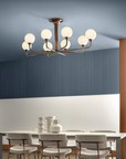 A dining room with contemporary design featuring blue walls and the Masiero Tee Chandelier.