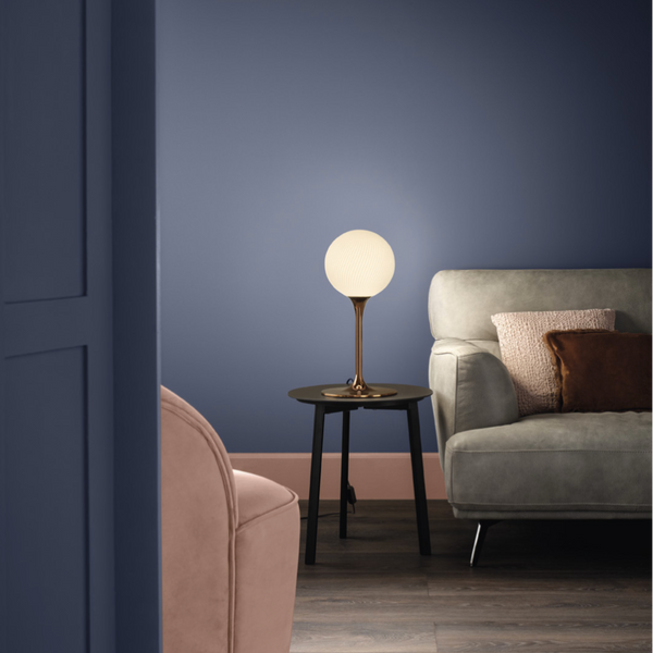 A living room with blue walls and a pink couch, adorned with luxury lighting from Masiero, including a Masiero Tee Table Lamp.