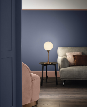 A living room with blue walls and a pink couch, adorned with luxury lighting from Masiero, including a Masiero Tee Table Lamp.