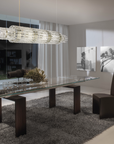 A modern dining room with a glass table and chairs featuring the Masiero Vegas Chandelier by Masiero lighting.