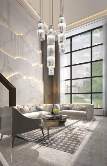 A modern living room with opulent marble floors and the stunning Masiero Vegas Double Height Chandelier, from Masiero brand's Vegas Collection, creating an atmosphere of luxury and enhanced by decorative lighting.