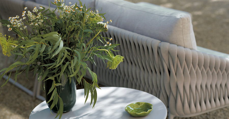 An Sifas Basket Sofa Collection with a vase of flowers on a table featuring waterproof properties.