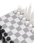 A chess board featuring the Skyline Chess Acrylic 2 City London New York Marble Board, with black and white chess pieces inspired by the iconic skylines of London and New York.