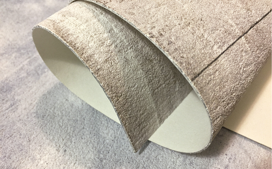 A close-up view of a hand-crafted fresco roll, made in Italy, showcasing its delicate texture created with a blend of Carrara marble and Roman travertine powder. 