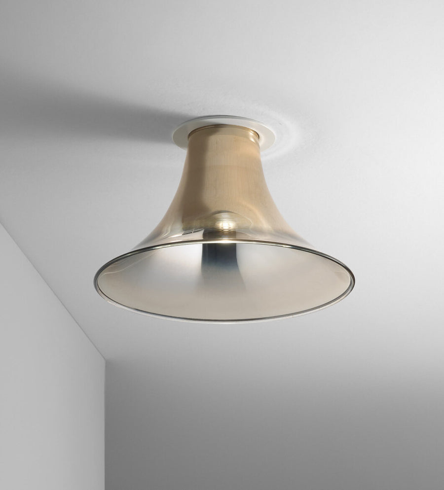 Baffo Collection by Italamp with conical design, titanium finish glass, and matching metal accents, showcasing Italian craftsmanship and elegance. A ceiling lamp in gold finish on a white ceiling