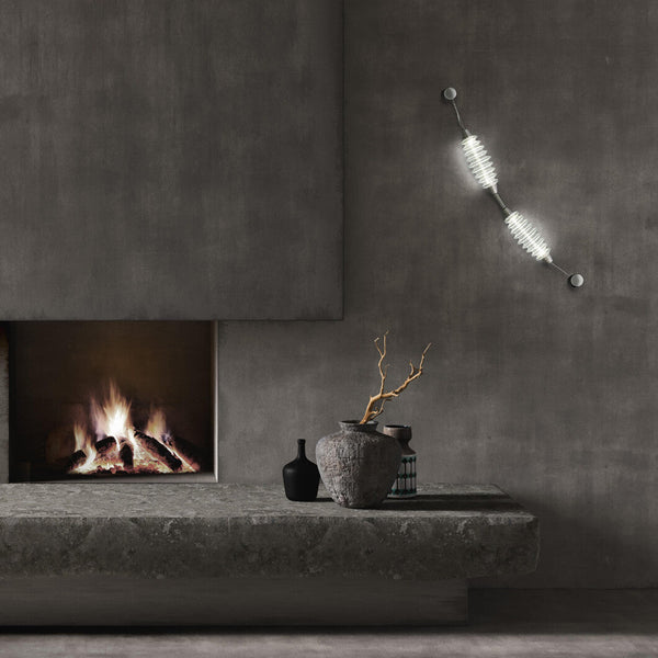 Colier collection by Italamp, featuring modular blown glass elements in vibrant colours and shapes, designed by Marc Sadler to create magical lighting effects. Set on a dark theme interior on the wall next to a fireplace and art objects
