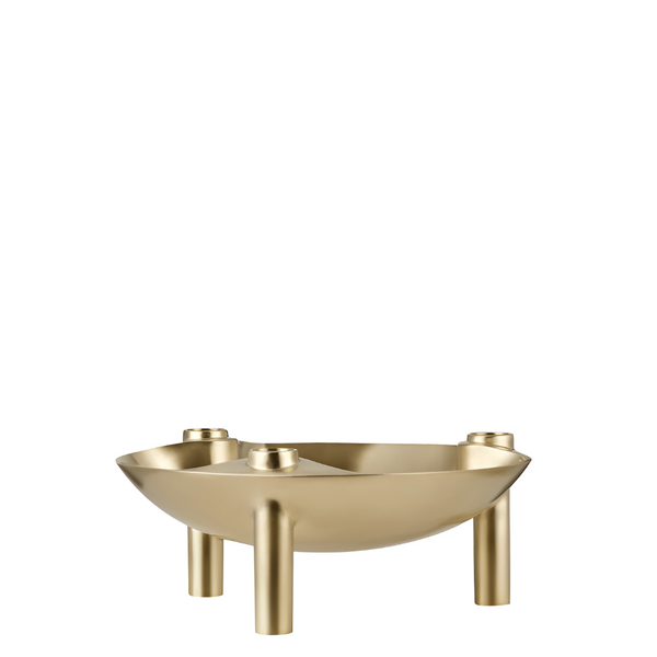 A modern three-legged metal candle holder with a shallow bowl shape and three cylindrical legs, finished in a brushed gold or brass-like metallic finish, shown on a plain white background.