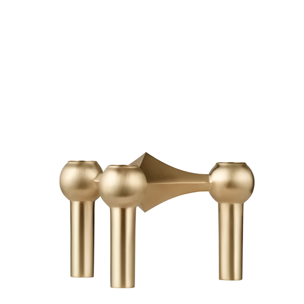 A modern three-spoke brass candle holder with spherical finials and cylindrical legs, shown on a plain white background from Stoff Nagel, available at Spacio in India. 