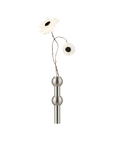 A modern wall-mounted vase with a brushed silver metal finish, featuring two spherical bulb details on a straight stem, holding two white daisy-like flowers with dark centers, set against a solid white background.