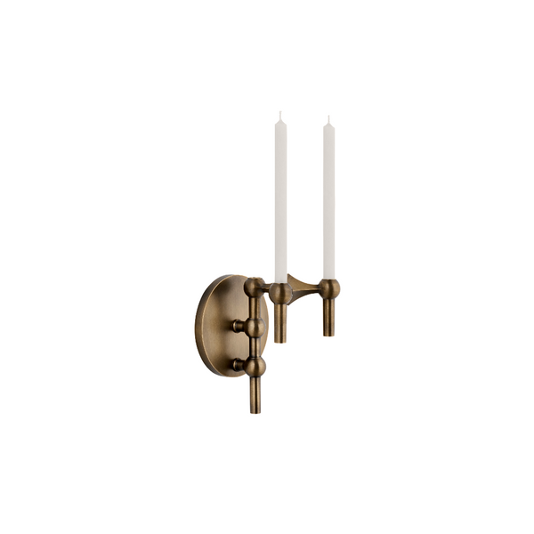 An antique bronze wall sconce with two candle-style arms holding white taper candles, shown against a plain white background.