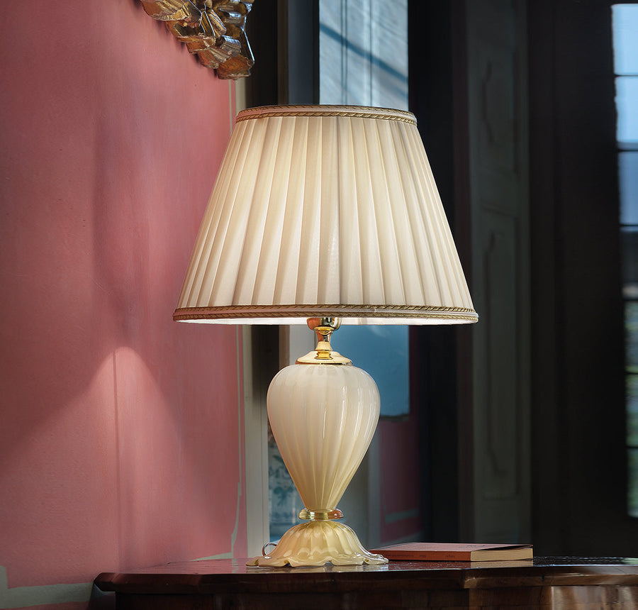 A Venetian cream colour glass table lamp with fabric shade on a round coffee table in a modern contemporary luxury interiors
