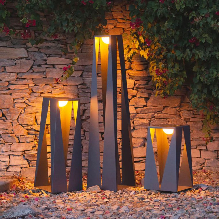 Decorative outdoor indoor portable and USB rechargeable solar lanterns with a stone wall and plants in the background  by Les Jardins from Spacio retail stores in India. 
