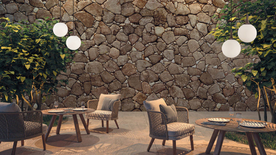 Outdoor seating area with stone wall and round tables.