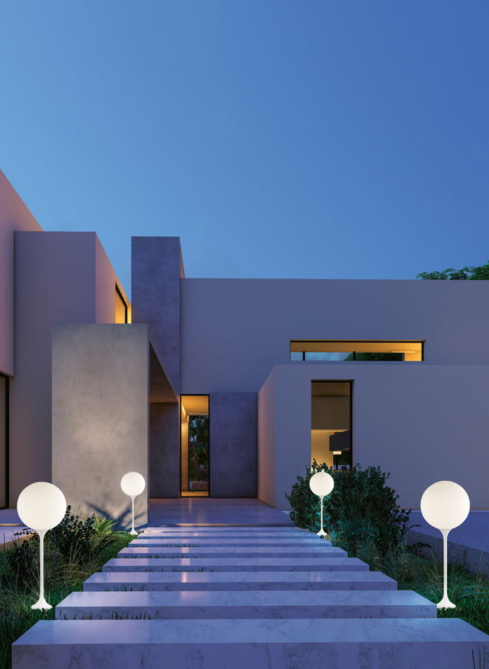 Modern house exterior with illuminated steps and spherical floor lamps at dusk.