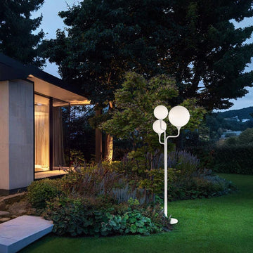 Modern outdoor lamp from Maserio in a garden setting with a house in the background