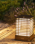 Solar-powered outdoor lamp illuminating a garden path with plants and flowers in the background.