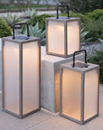 Three solar-powered outdoor lanterns on a patio with greenery in the background  by Les Jardins available at Spacio retail stores in Mumbai & Kolkata. 