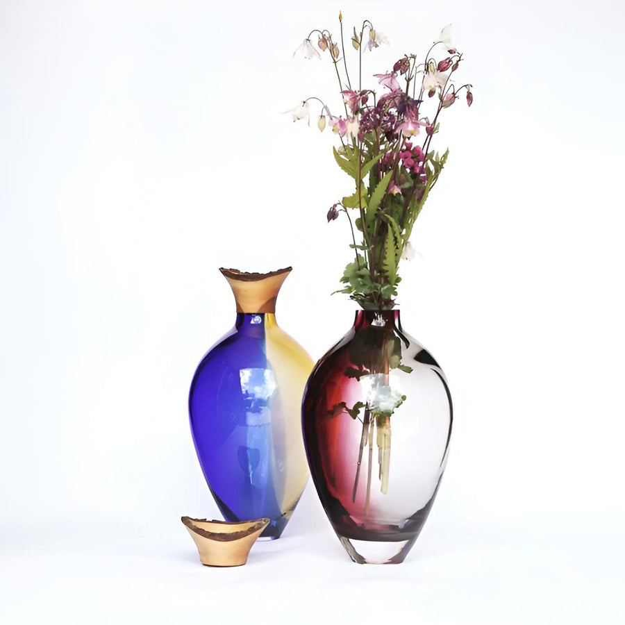 Two colourful sculptural vases from Utopia & Utility with one containing flowers on a white background, available at Spacio retail stores in Mumbai & Kolkata. 