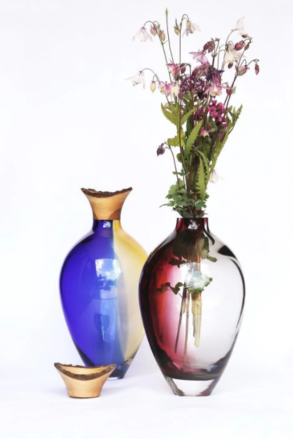 Two colorful vases with one containing flowers on a white background