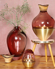 Decorative vases with gold accents on a wooden surface against a pink checkered background