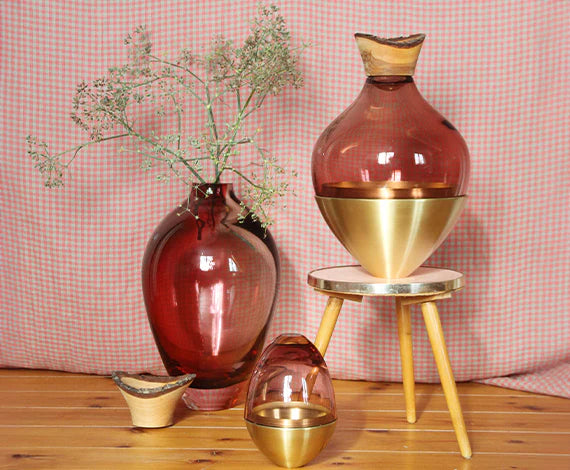 Decorative vases with gold accents on a wooden surface against a pink checkered background