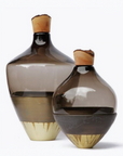 Two glass sculptural vases with wood top on a white background