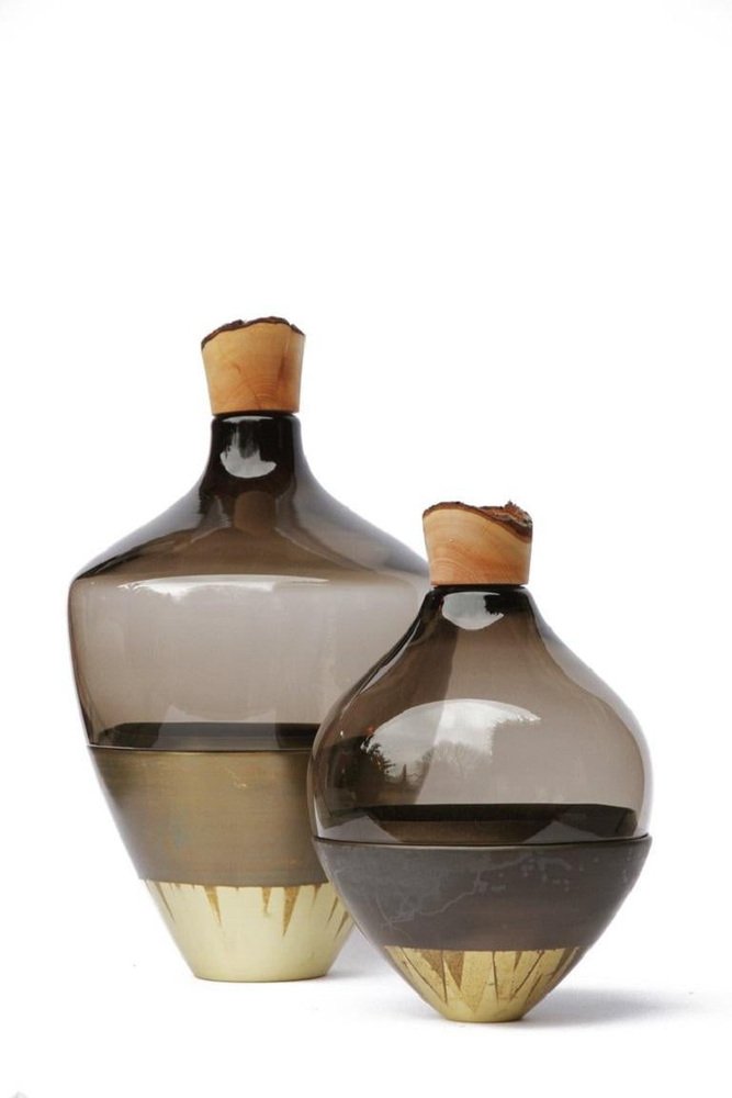 Two glass sculptural vases with wood top on a white background