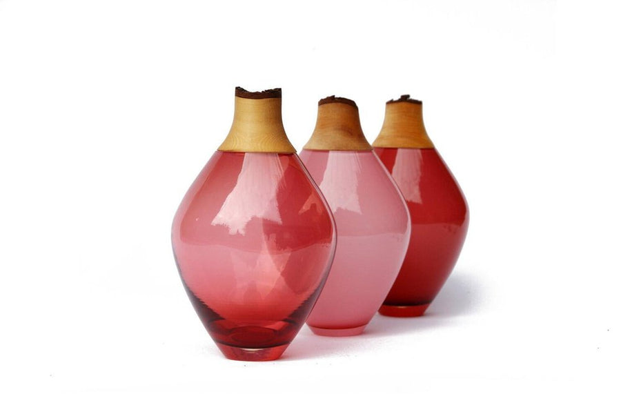 Three glass sculptural vases with wood accents on a white background