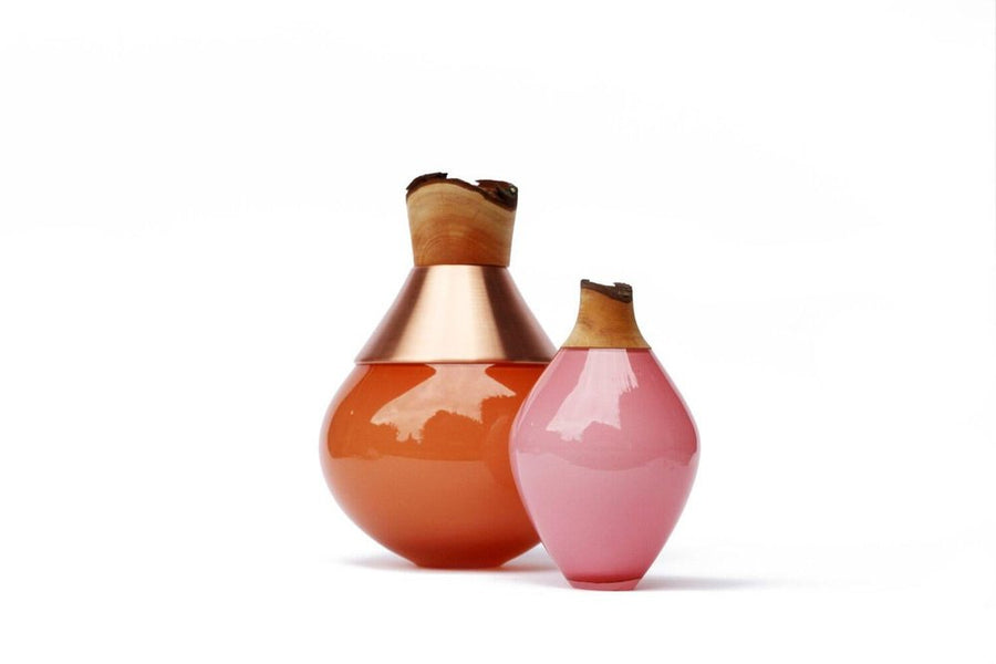 Two decorative vases, one orange and one pink, with wooden tops on a white background.