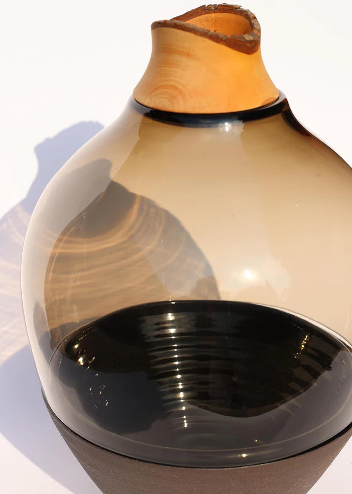 Sculptural Glass Vase with a wooden top and black base on a white background from Utopia & Utility, available at Spacio retail stores in Mumbai.