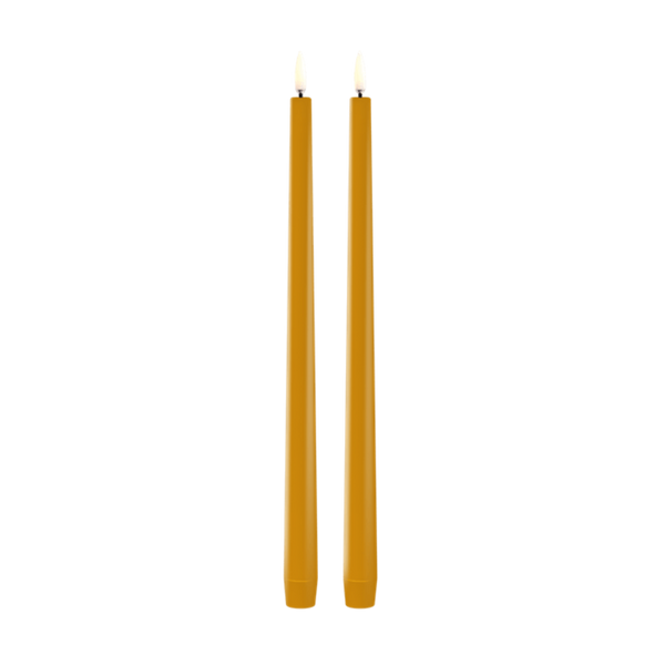 Two tall, thin led taper candles in a warm mustard yellow color, standing upright side-by-side against a solid white background.