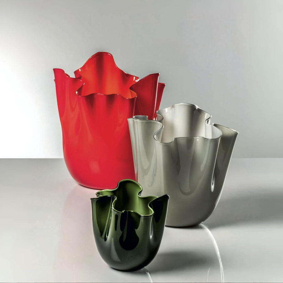 Three colorful venini murano vases (red, silver, green) on a reflective surface with a light gray background at Spacio retail store in Mumbai
