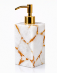 White quartz soap dispenser with gold accents on a white background