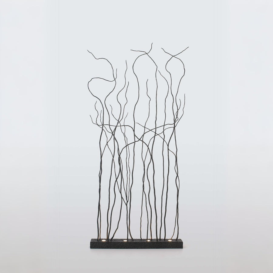 Decorative metal floor lamp with branch-like patterns on a light gray background