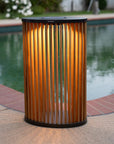 Cylindrical outdoor solar light lantern with corrugated design near a pool by Les Jardins available at Spacio retail stores in Mumbai & Kolkata. 